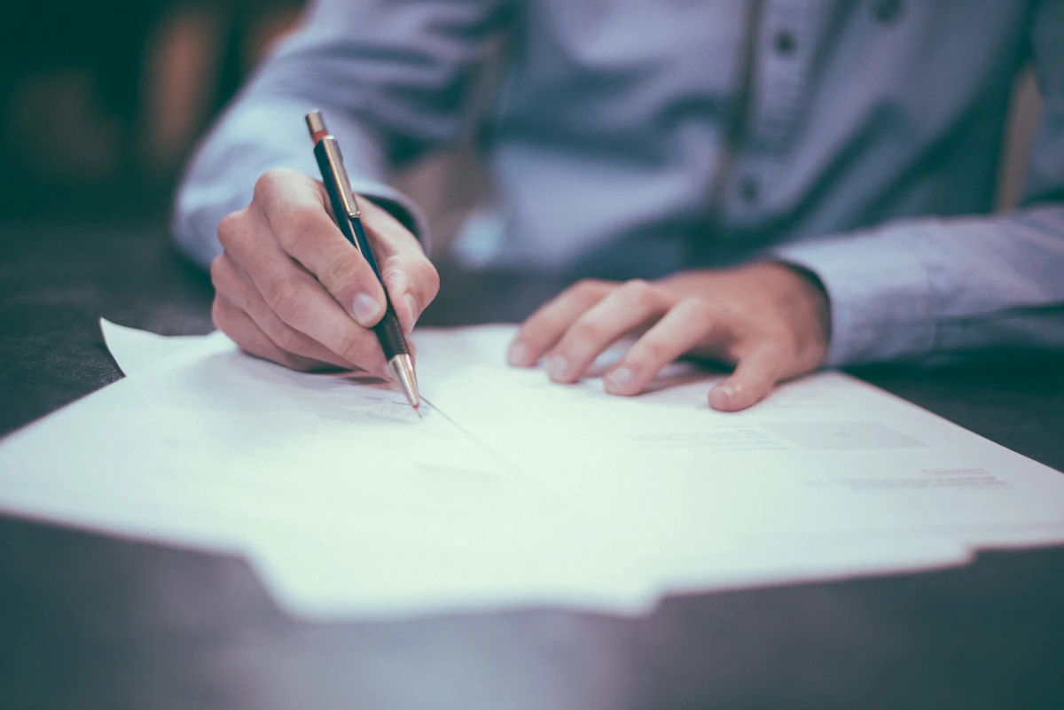 Finance professional reviewing and signing paperwork at a desk